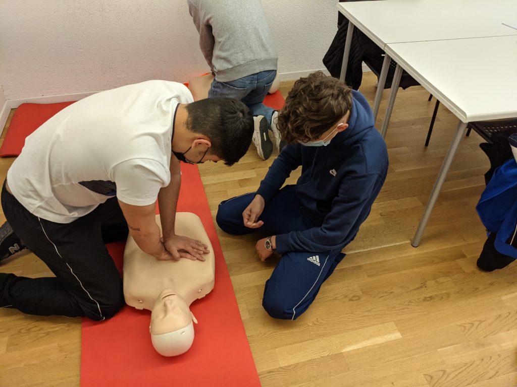 Formation d'un jeune homme au massage cardiaque dans le cadre d'un atelier sur les gestes de premiers secours lors d'une journée sécurité